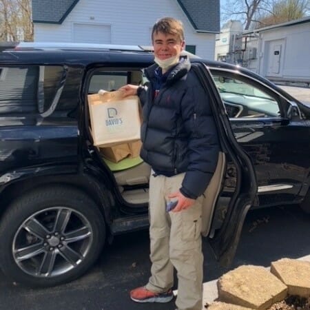 Man unloads paper bags from a car.