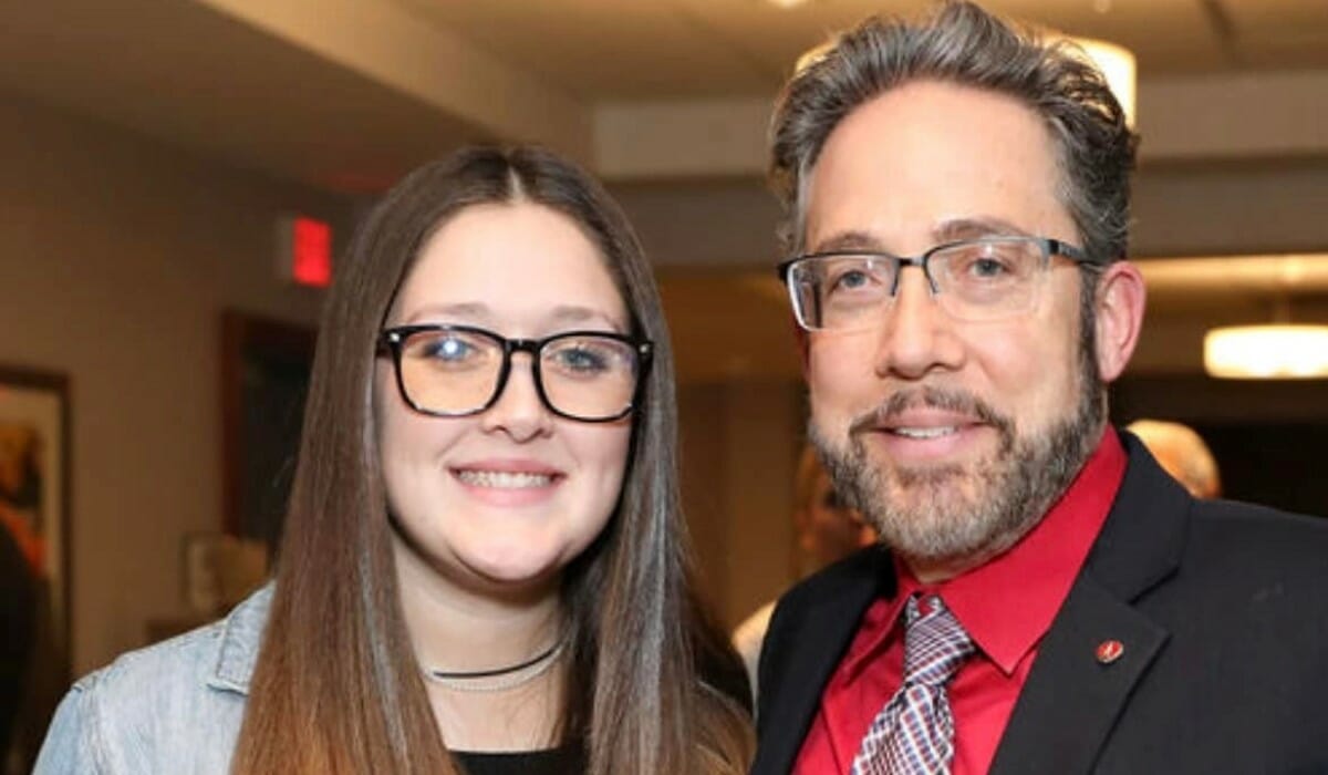 Two people in dress clothes stand together.