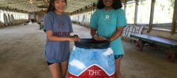 Two people stand with a large barrel painted artistically.