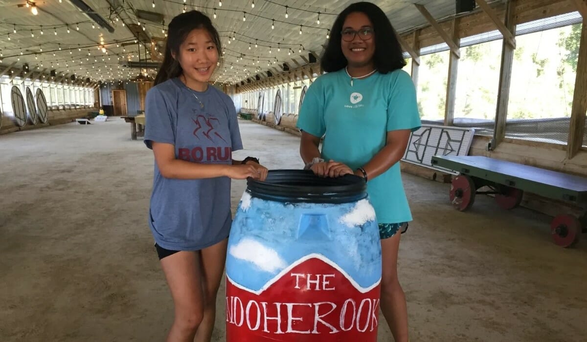 Two people stand with a large barrel painted artistically.