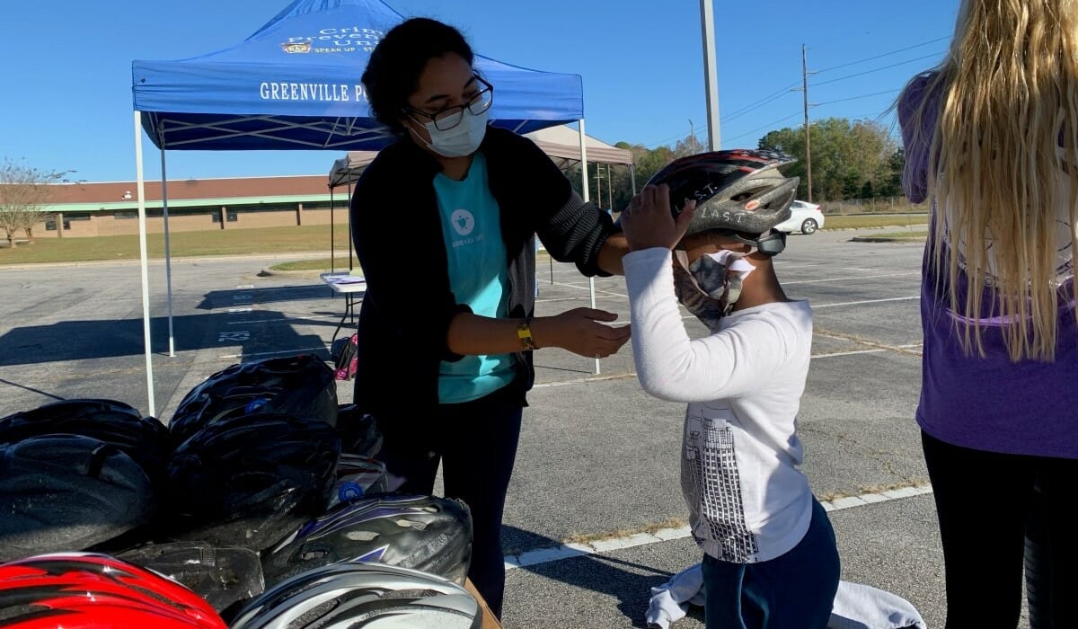 Person helps fit a bicycle helmet on a small child.