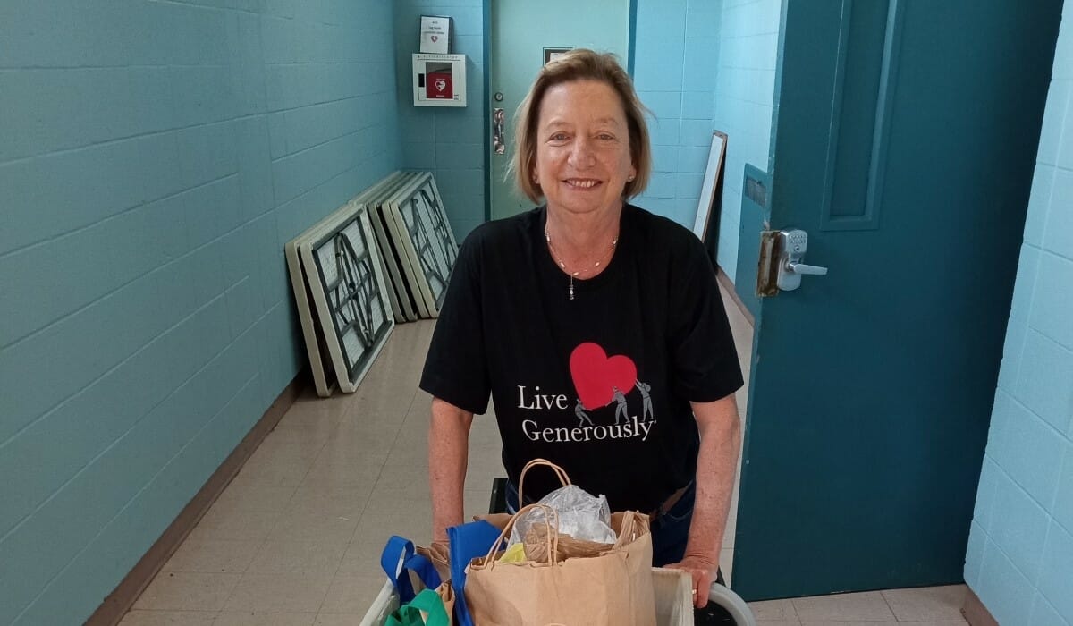 Woman pushes a cart of donated food.