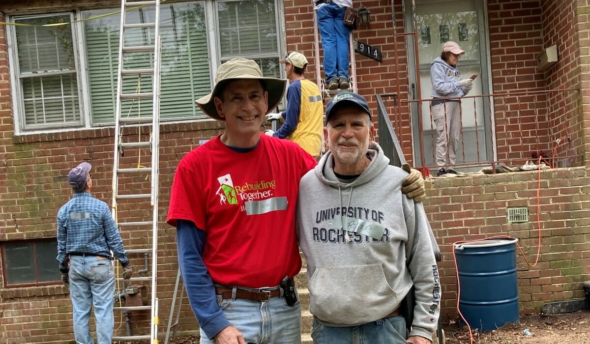 Two men standing in front of a house with construction in the background.