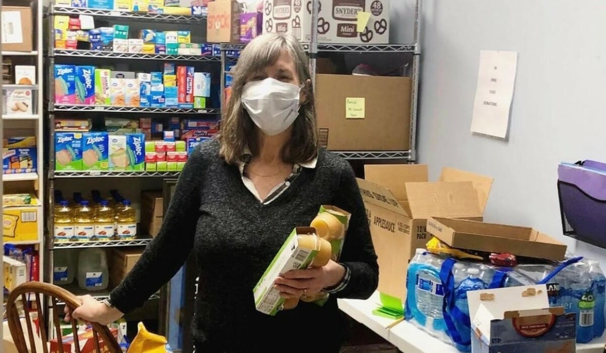Woman standing in a stocked food pantry.