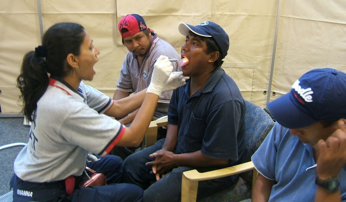 Woman uses a small flashlight to examine a patient's throat.