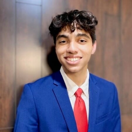 Person in a blue suit and red tie smiling.