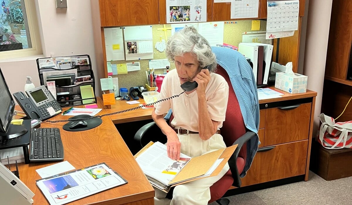 Woman seated at a desk speaking on the phone.