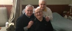 Group of three people with white hair pose together.