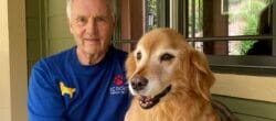 Man in a blue shirt poses with golden retriever.