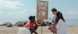 Family doing a beach clean up together with a sign that reads, "Save the Earth"